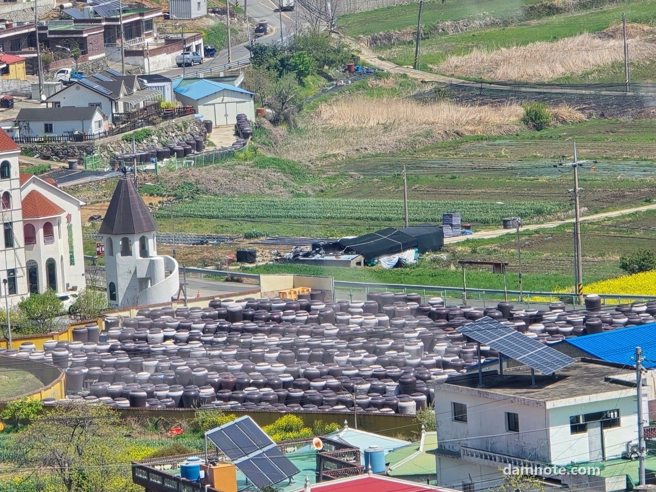 남해 언덕 위에서 내려다본 마을, 붉은 지붕과 밭, 첨탑이 있는 건물, 2026년 4월 11일 12시 38분 직접 촬영